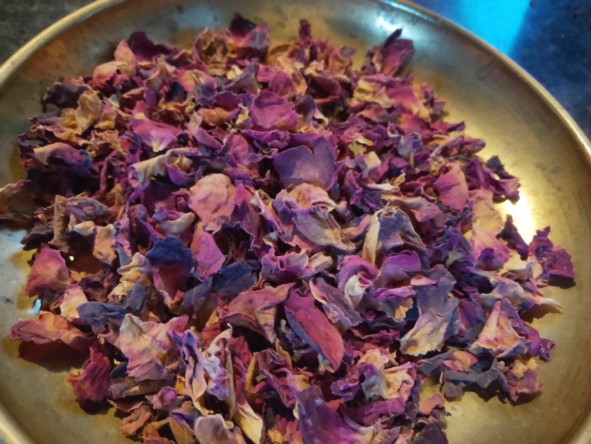 Deep red and pink dried rose petals on a brass dish