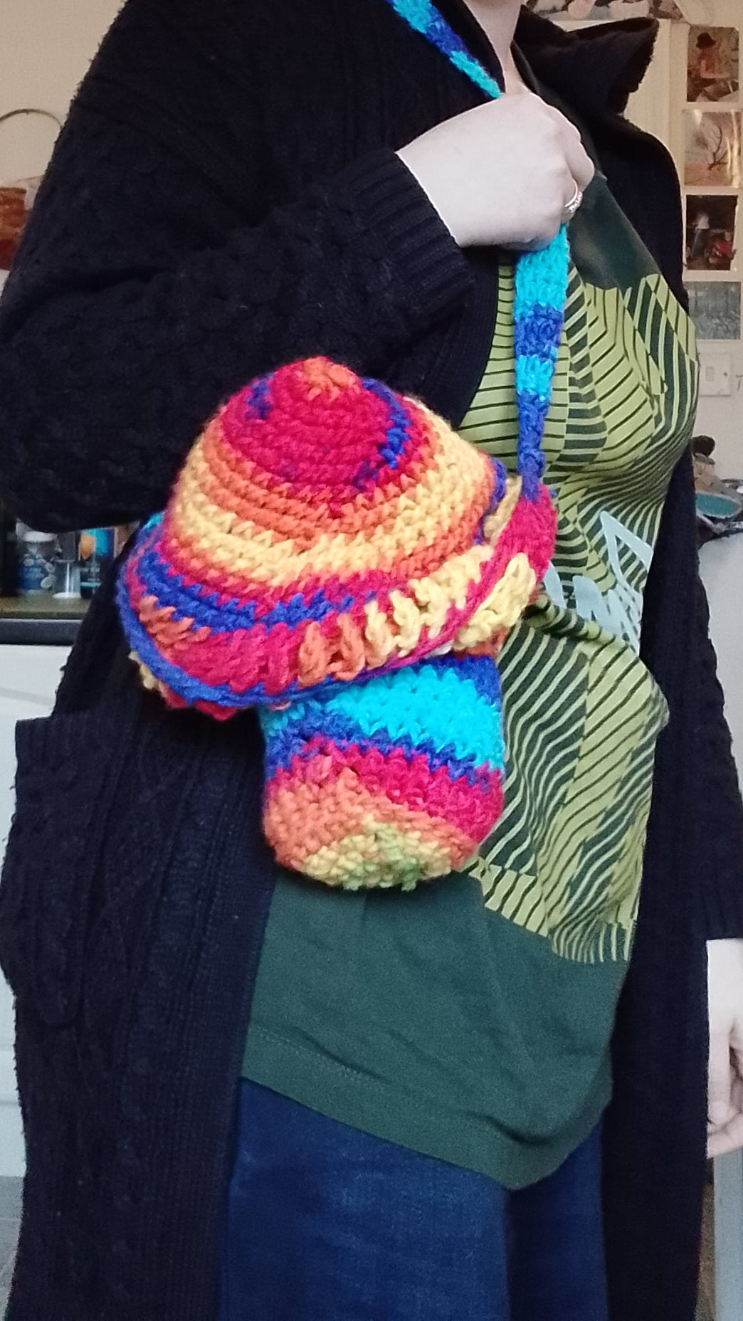 Person holding a colourful crochet mushroom-shaped bag with blue shoulder strap